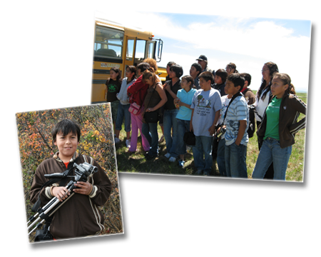 Children on a field trip listening to an elder (out of frame) and taking pictures.