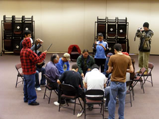 Elders and Kainai High School students in a drum circle.