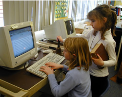 Picture of girls sitting and working on the computer.